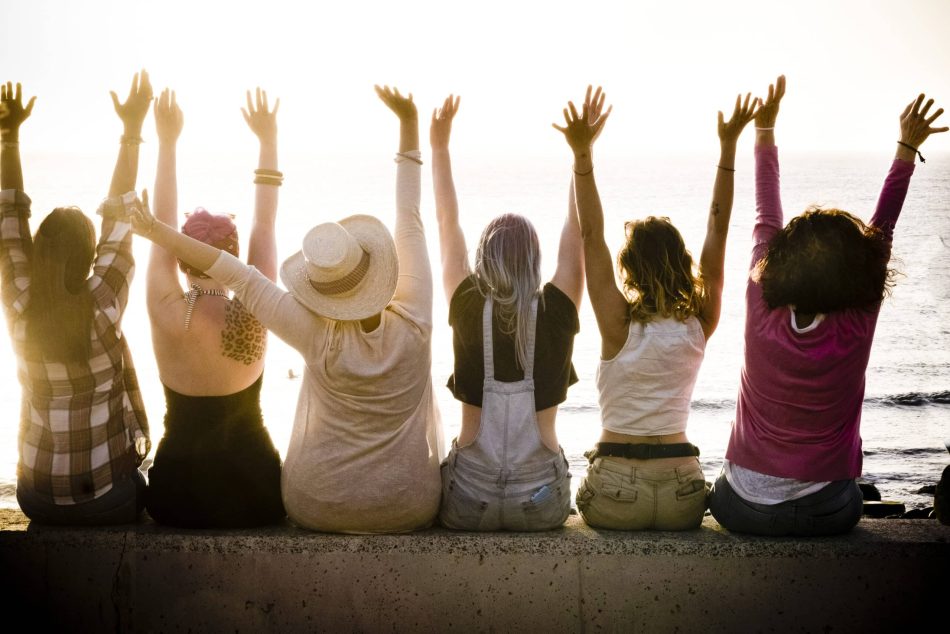 rear view of group of females caucasian friends enjoying at the sunset with ocean in background - success and satisfaction concept for nice people together with joy - friendship and vacation